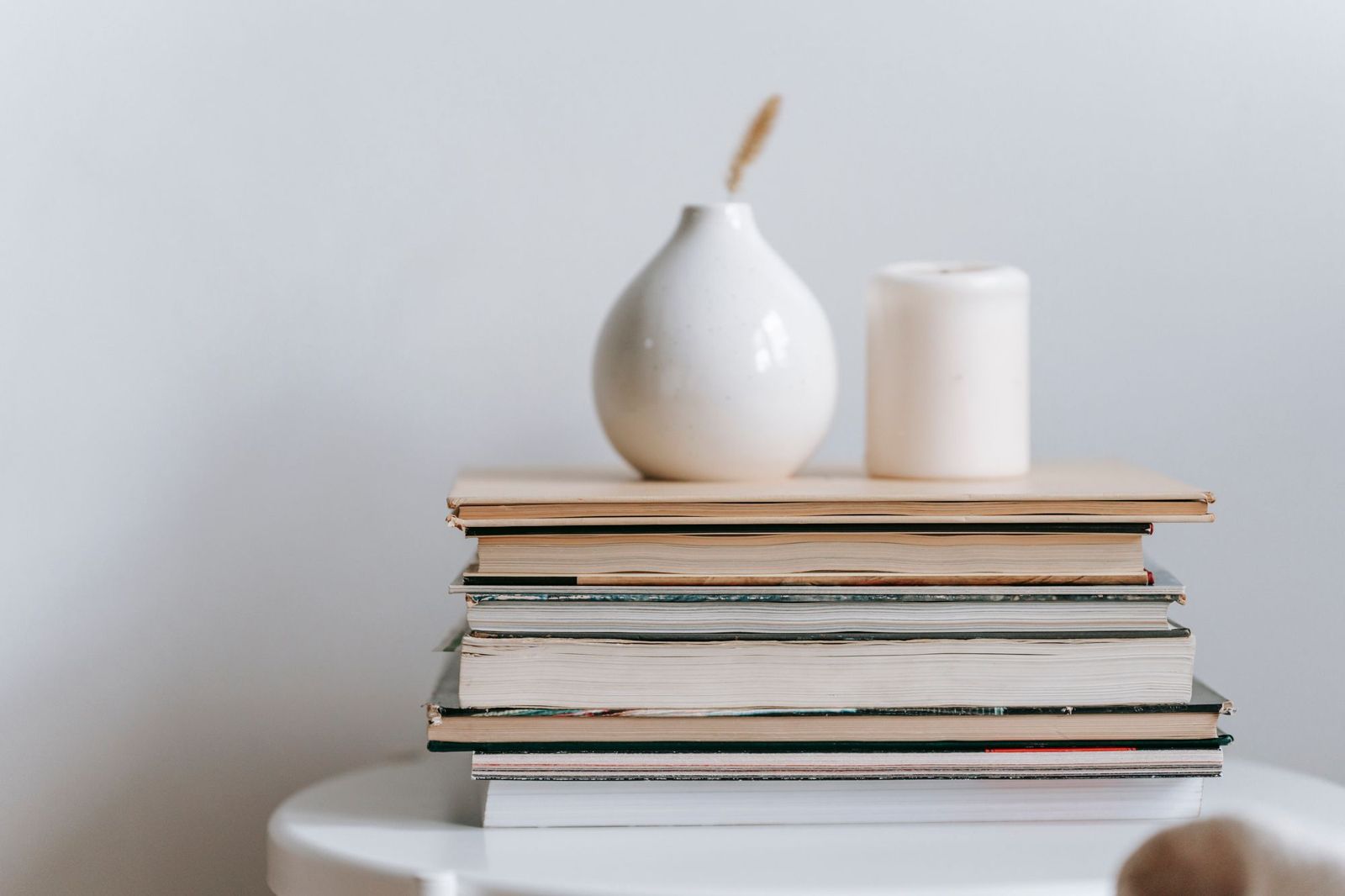White ceramic vase and candle on a stack of books